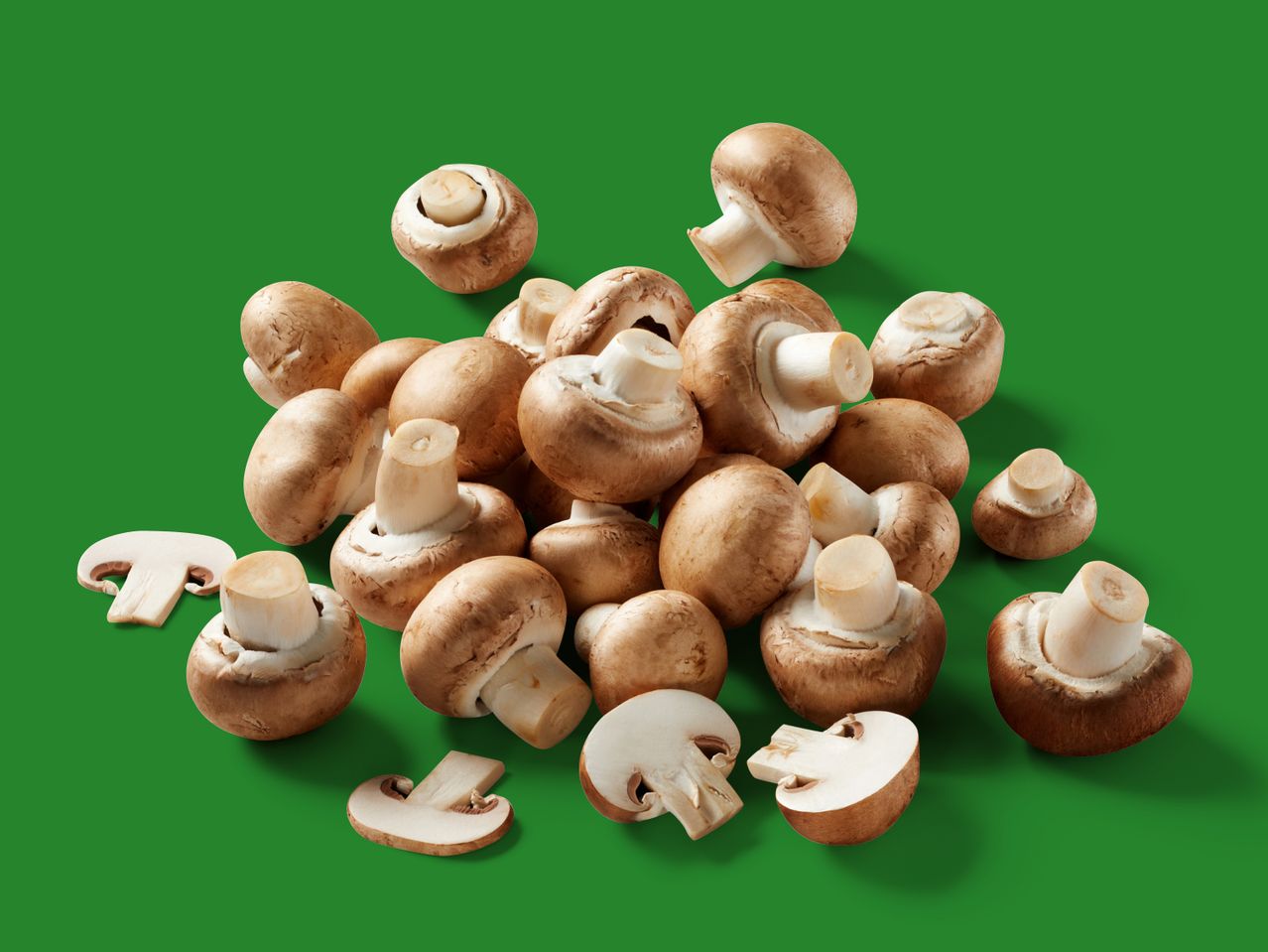 Viele braune Champignons vor grünem Hintergrund.