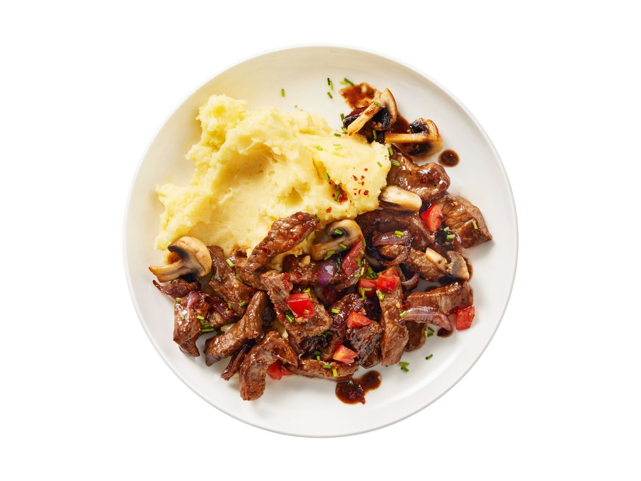 Beef stir-fry with mashed potatoes, mushrooms, and vegetables on a white plate.
