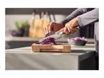 A person slicing red cabbage on a wooden cutting board with a chef's knife.