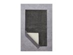 Dark gray bath mat on a tiled floor, with one corner folded to show the backing.