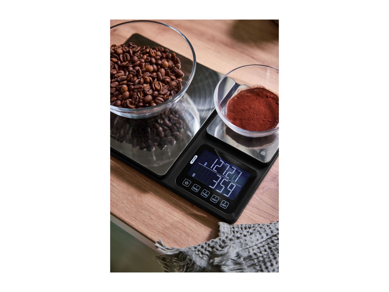 Digital kitchen scale with coffee beans and ground coffee in bowls, displaying measurements.