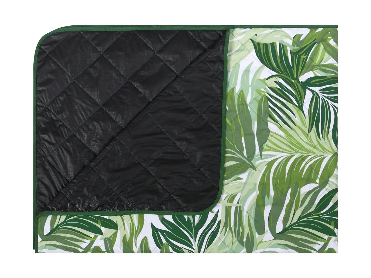 Folded picnic blanket with a tropical leaf pattern on one side and a black quilted underside.