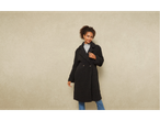 Donna in cappotto nero effetto Teddy, dolcevita grigio e jeans blu.