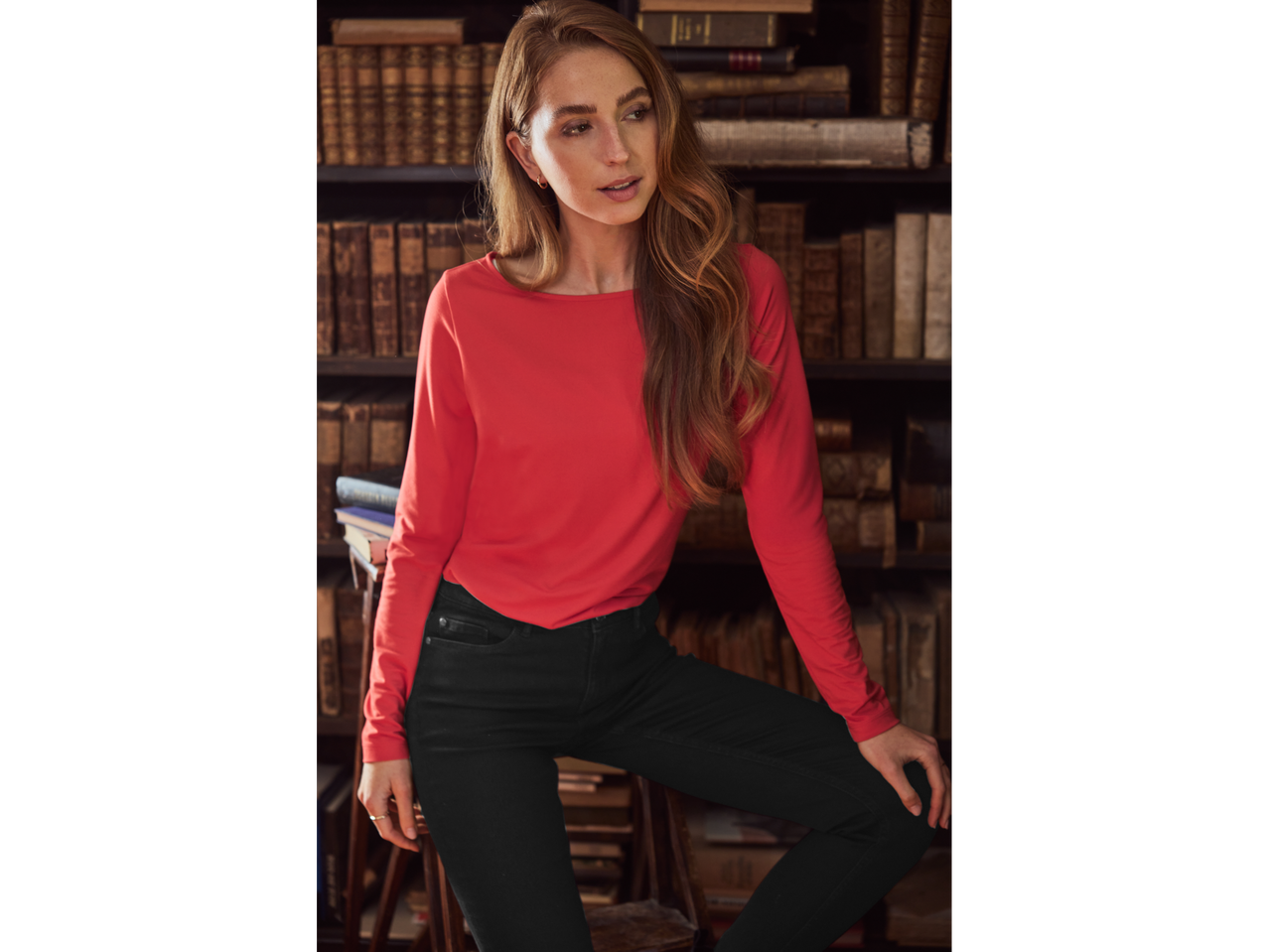 Woman in red long-sleeve top and esmara® Ladies' Skinny Jeans in a library setting.