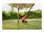Orange electric grass trimmer cutting grass around a tree in a garden.