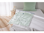 Vacuum storage bag with a light green duvet inside, on a bed with a matching pillow.