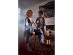 Two children in Halloween costumes stirring a cauldron in a spooky, smoke-filled room.