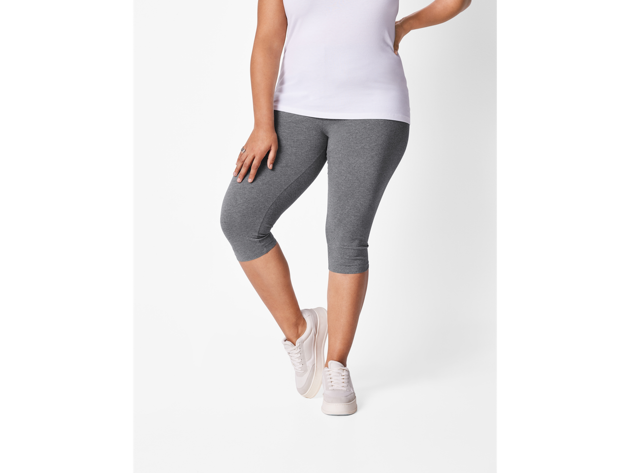 Femeie purtând leggings scurți gri și adidași albi.