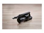 Black handheld vacuum cleaner with a brush attachment on a light wooden floor.