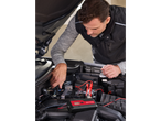 A man connects an Ultimate Speed battery charger to a car engine.