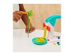 Child playing with a pasta maker toy, making yellow and green playdough noodles.