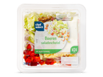 Een salade met sla, paprika, ui, kaasblokjes, walnoten en yoghurtdressing in een plastic verpakking.