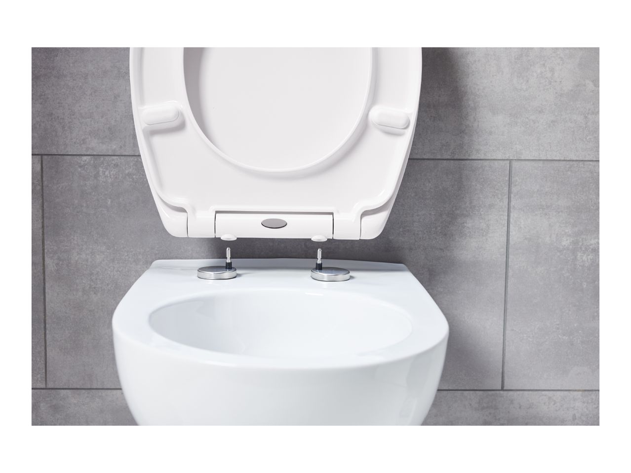 A white toilet with the seat and lid raised against a gray tiled wall.