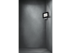 A motion sensor LED floodlight in a grey room corner.