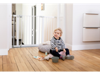 Baby playing near a Saftey 1st baby gate and toys.