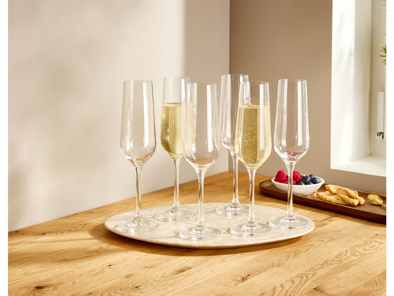 Flutes de champanhe SILVERCREST® com bebidas e aperitivos numa mesa de madeira.
