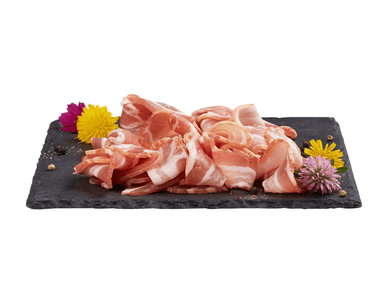 Tranches de bacon cru sur une ardoise noire, garnies de fleurs et de grains de poivre.