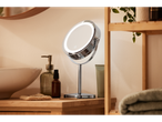 A lighted vanity mirror on a wooden bathroom counter with a sink and toiletries.
