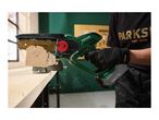 A person cutting a wooden log with a cordless mini chainsaw, sawdust flying around.
