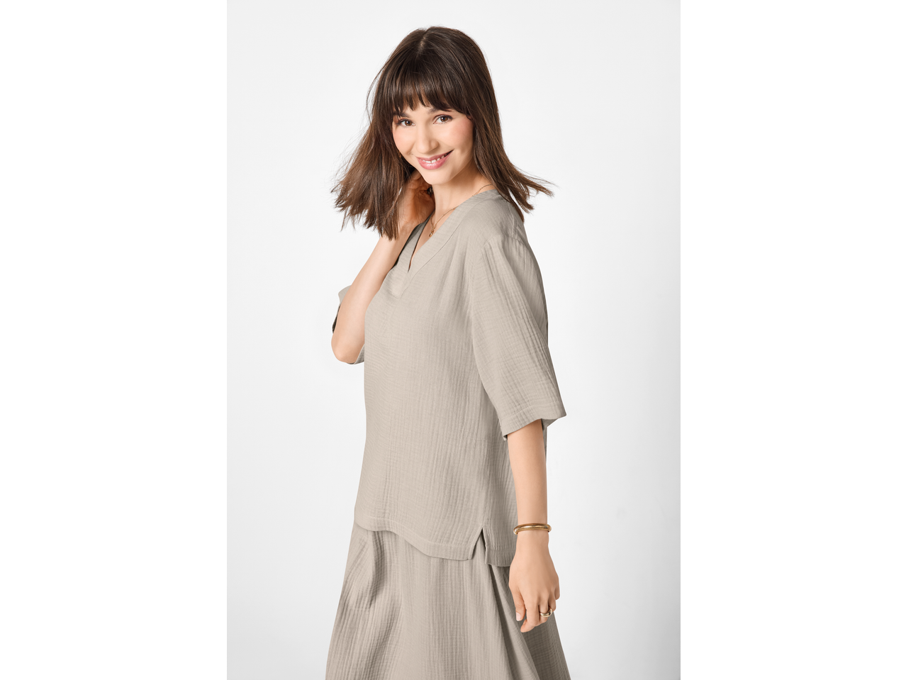 Femeie zâmbitoare în top de muselină bej ESMARA și fustă asortată.