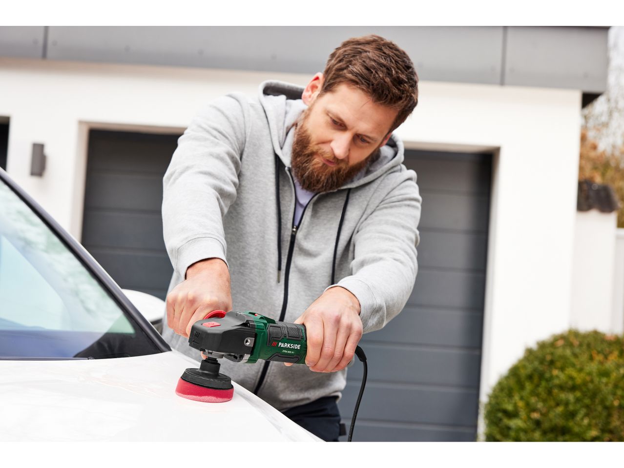 A man uses a Parkside polisher to detail a car.