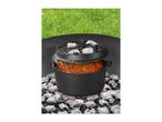 Dutch oven cooking chili outdoors on hot coals with a green grass background.