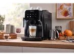 A SilverCrest coffee machine making a latte, with fruit and other kitchen items on a counter.