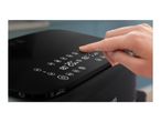 A hand touching the digital display of a black air fryer, showing various cooking settings.