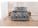A grey upholstered bed with a floral duvet cover and matching pillows sits in a light and airy bedroom.