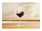 Red wine swirling in a glass on a wooden kitchen counter.