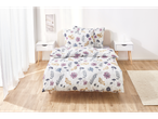 A bed with floral bedding and matching pillows sits in a bright bedroom.