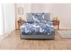 Grey upholstered bed with blue crane-print bedding set.
