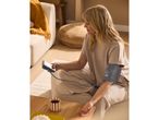 Woman measuring blood pressure at home with a blood pressure monitor.