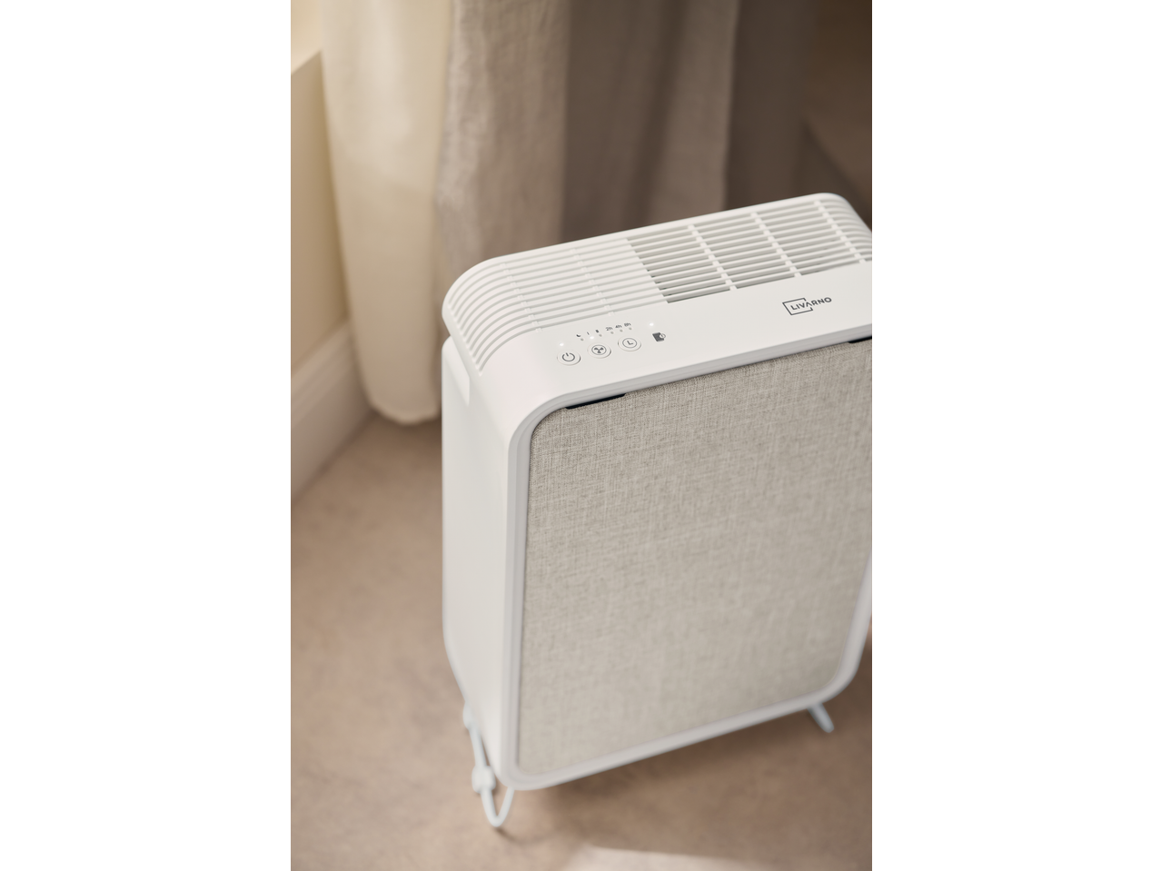 Purificator de aer LIVARNO alb cu panou de control și față din material textil, lângă o perdea.