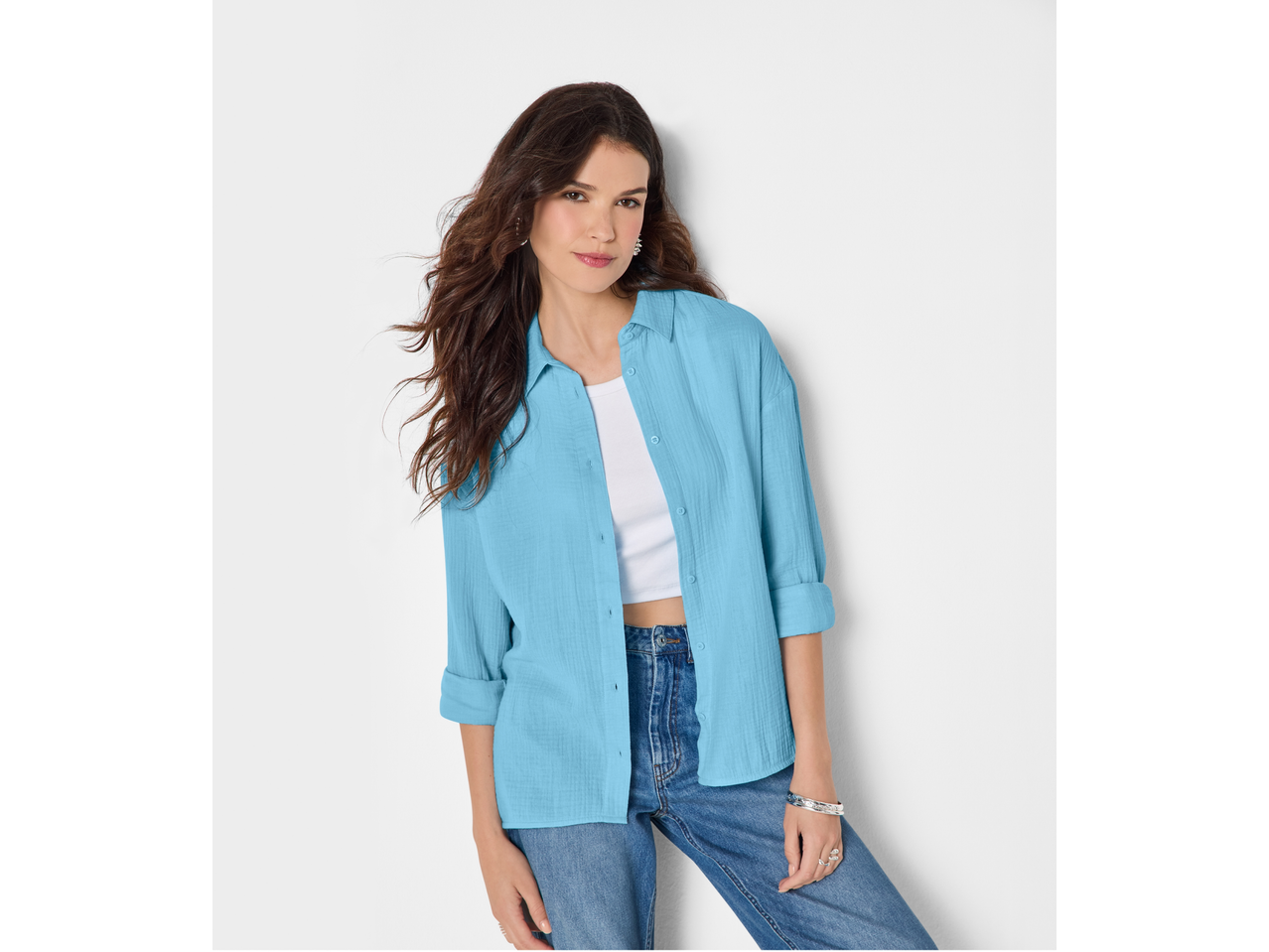 Femeie purtând cămașă de muselină ESMARA albastru deschis, top alb și blugi.