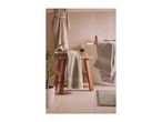 Bathroom with light grey towels on a wooden stool and hanging over a bathtub.