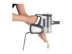Person emptying a handheld vacuum cleaner, showing collected debris falling out.