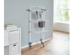 White and blue clothes drying rack with clothes on it, next to a white storage unit.