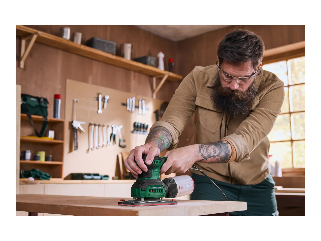 Man sanding wood with a Parkside orbital sander in a workshop.