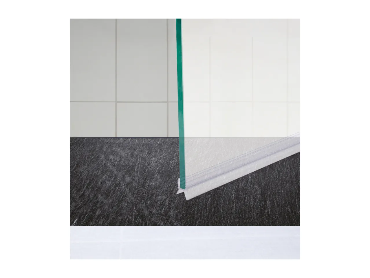 Shower door with a clear plastic seal at the bottom, against a dark floor.