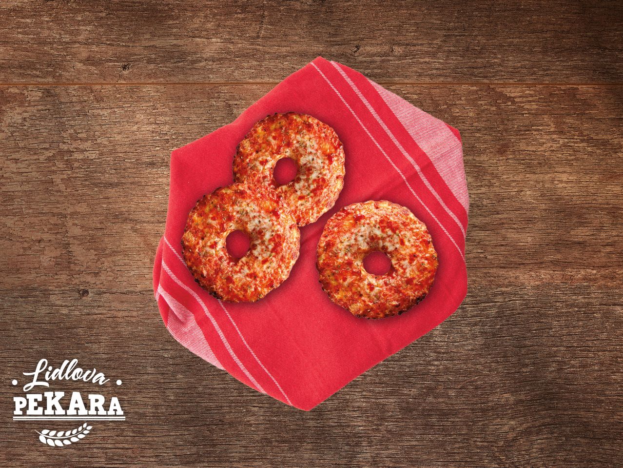 Tri Lidlova pekarska pizza krafne na crvenom stolnjaku.