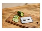 Cucumber slices and a stainless steel mandoline on a wooden cutting board.