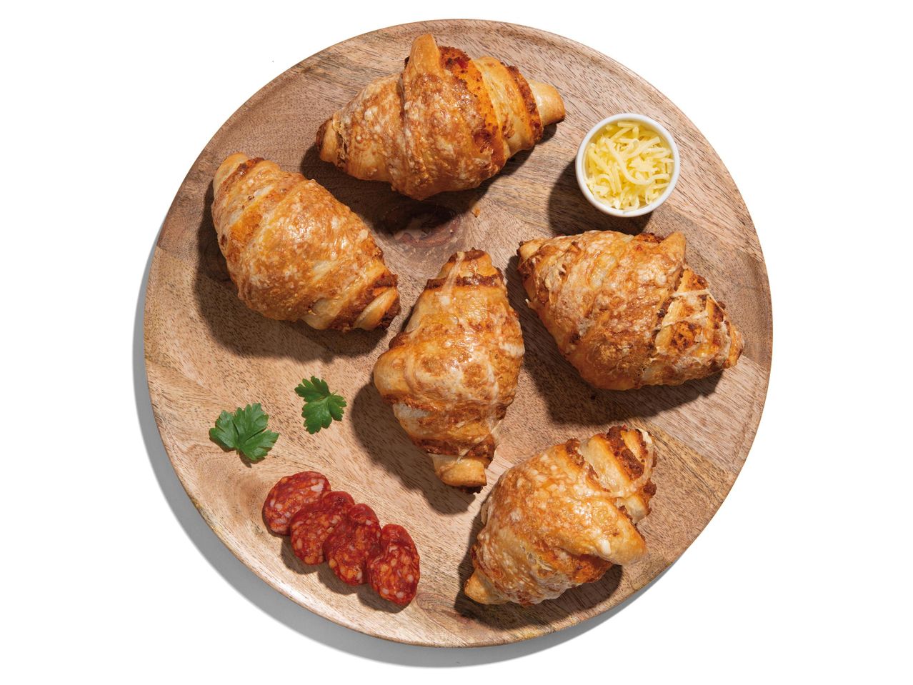 Sajtos-szalámis croissant-ok fa táblán.