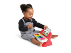A baby playing with a Hape musical toy piano with colorful keys and a screen showing sheet music.