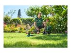 Man watering a garden with a sprinkler and hose reel cart on a sunny day.