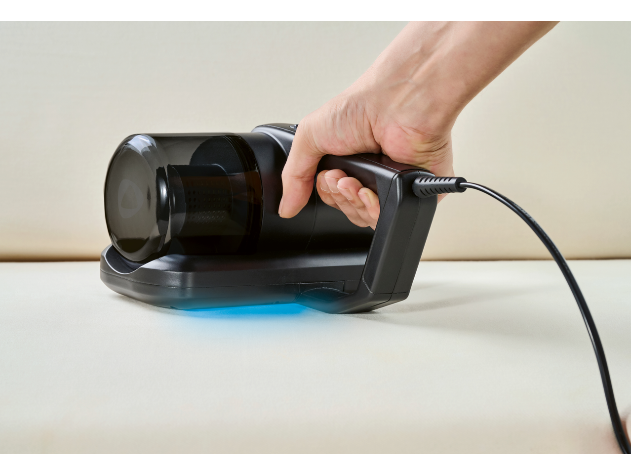 Aspirador anti-ácaros SILVERCREST em uso, com luz UV azul visível.