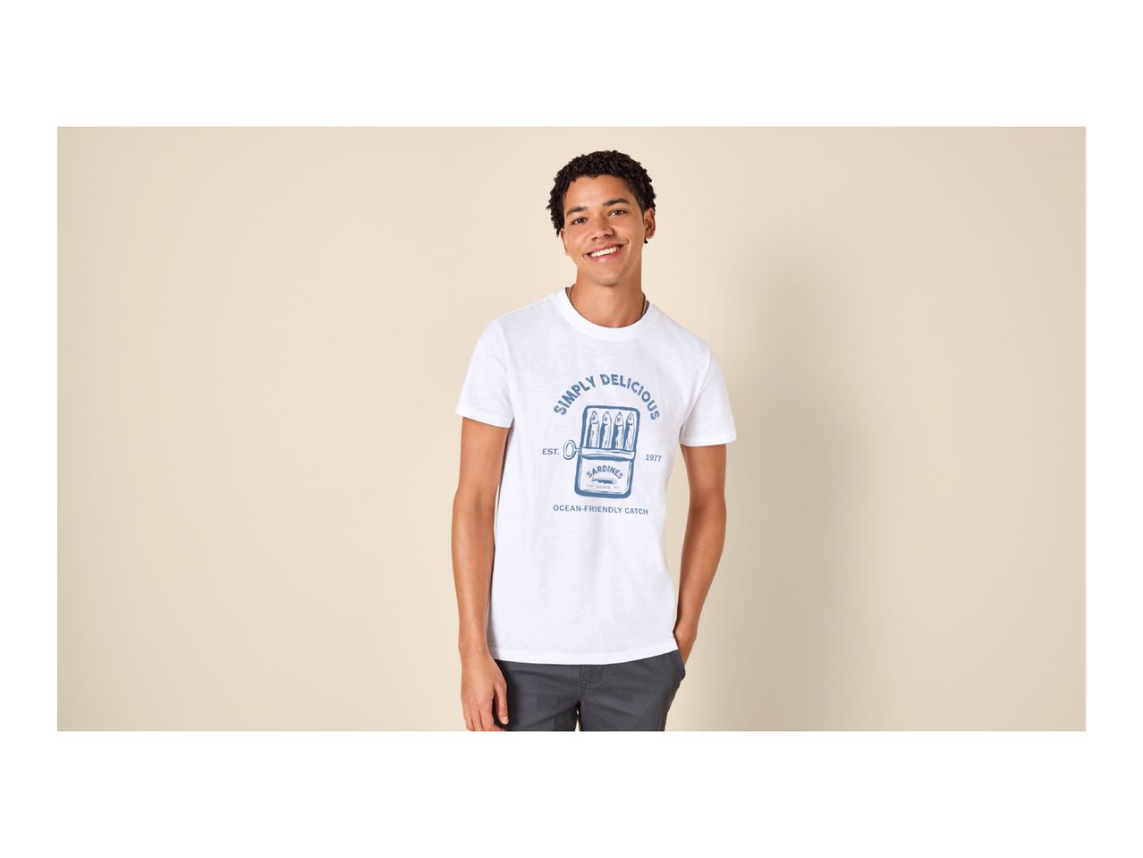 A man in a white t-shirt with a blue sardine can graphic that says 'Simply Delicious'.