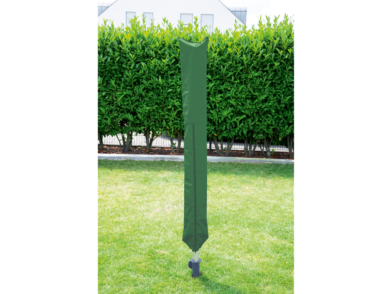 Green rotary dryer cover in a garden with a hedge and house in the background.