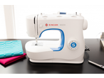Máquina de costura E-ELEMENT BY PFAFF M3205 branca com detalhes azuis e tecidos.