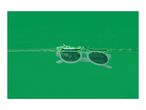 White sunglasses floating in green water with splashes.